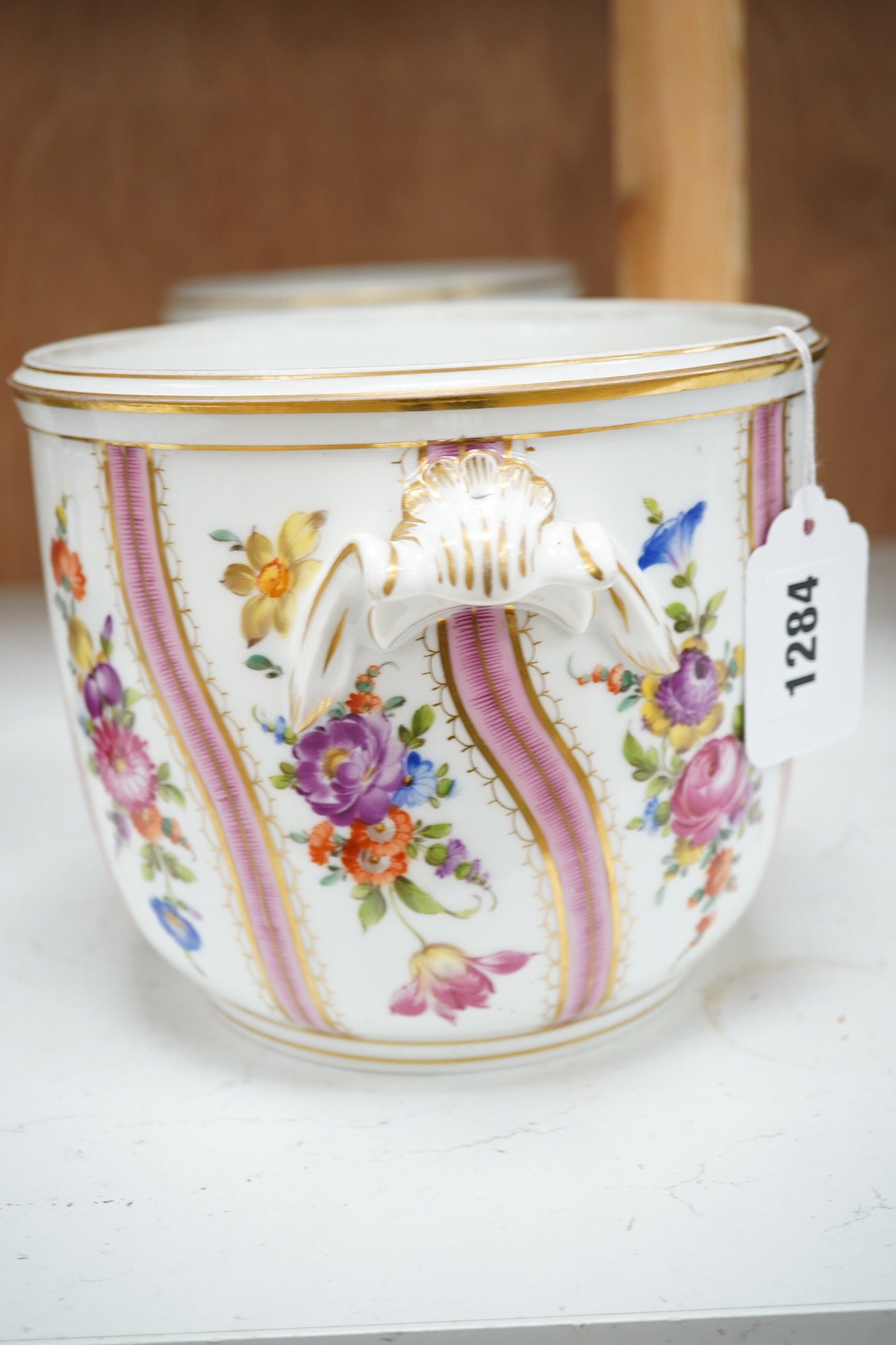 A pair of Dresden wine coolers with floral decoration, 15cm high, 18cm diameter. Condition poor to fair, cracks to the base of one.